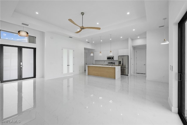 kitchen with a spacious island, french doors, pendant lighting, white cabinetry, and appliances with stainless steel finishes