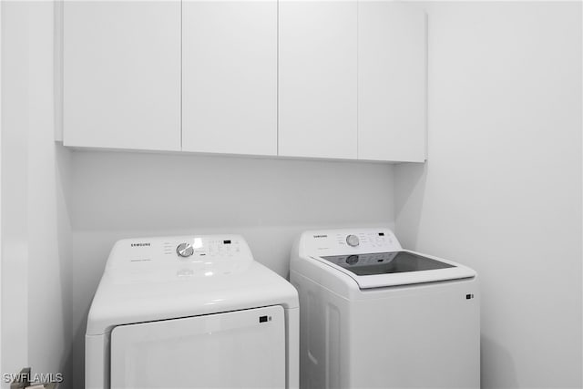 washroom featuring washer and dryer and cabinets