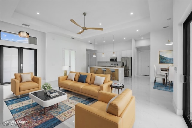 living room featuring a towering ceiling, french doors, ceiling fan, and a raised ceiling