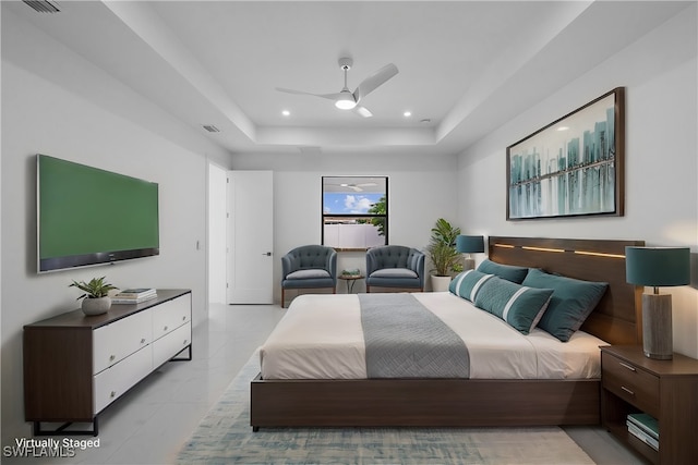 tiled bedroom with a tray ceiling and ceiling fan