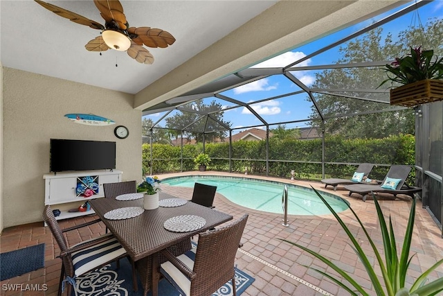 view of swimming pool with glass enclosure, ceiling fan, and a patio