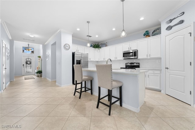 kitchen with a kitchen island with sink, hanging light fixtures, white cabinets, and stainless steel appliances