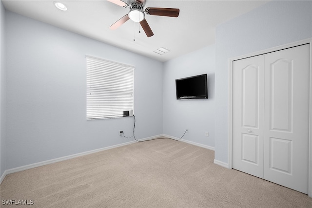 unfurnished bedroom featuring ceiling fan, a closet, and light carpet