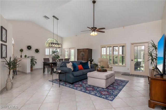 tiled living room with ceiling fan with notable chandelier and high vaulted ceiling