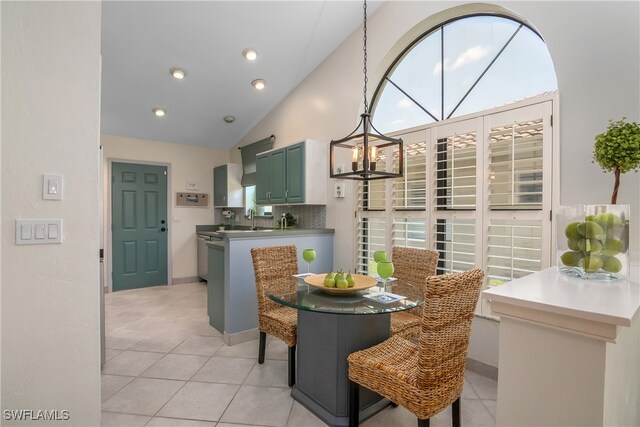 tiled dining area with lofted ceiling, a chandelier, and sink