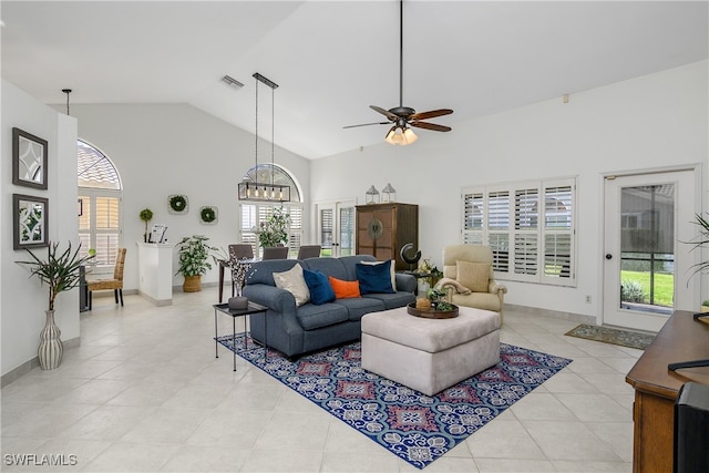 tiled living room with high vaulted ceiling and ceiling fan with notable chandelier