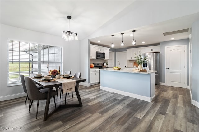 kitchen with pendant lighting, a kitchen island, white cabinetry, appliances with stainless steel finishes, and vaulted ceiling