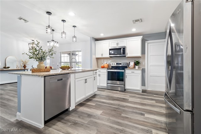 kitchen featuring white cabinets, appliances with stainless steel finishes, sink, and decorative light fixtures