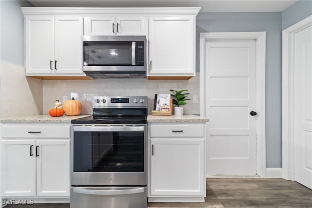 kitchen featuring appliances with stainless steel finishes, decorative backsplash, white cabinetry, and hardwood / wood-style floors