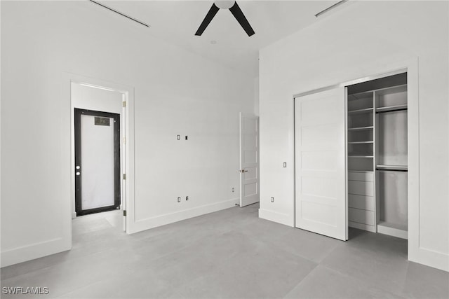 unfurnished bedroom with a closet, a towering ceiling, a ceiling fan, concrete flooring, and baseboards