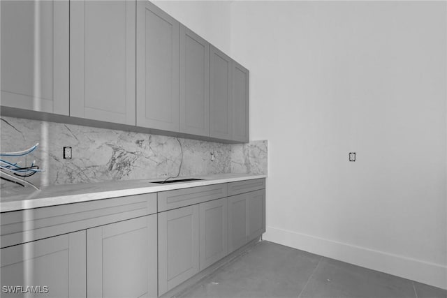 kitchen with light tile patterned floors, light countertops, backsplash, and gray cabinetry