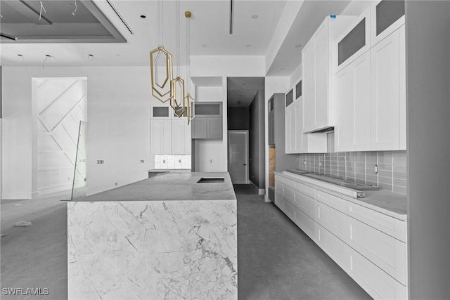 kitchen featuring finished concrete floors, white cabinets, and backsplash