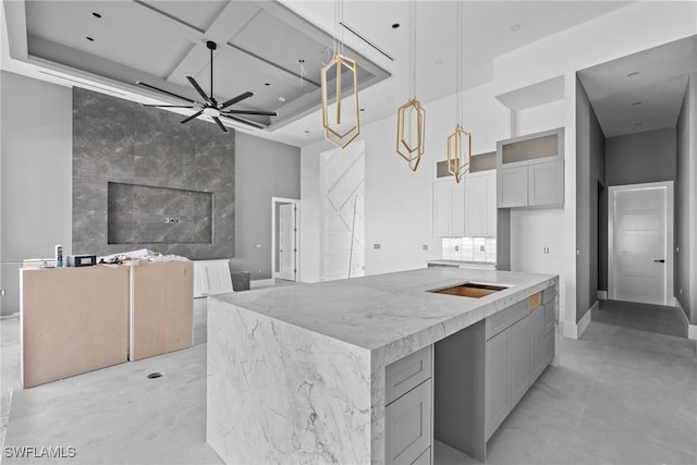 kitchen with gray cabinets, hanging light fixtures, a towering ceiling, ceiling fan, and coffered ceiling