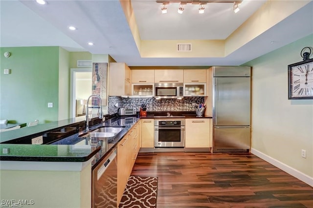 kitchen with sink, appliances with stainless steel finishes, kitchen peninsula, and dark hardwood / wood-style floors