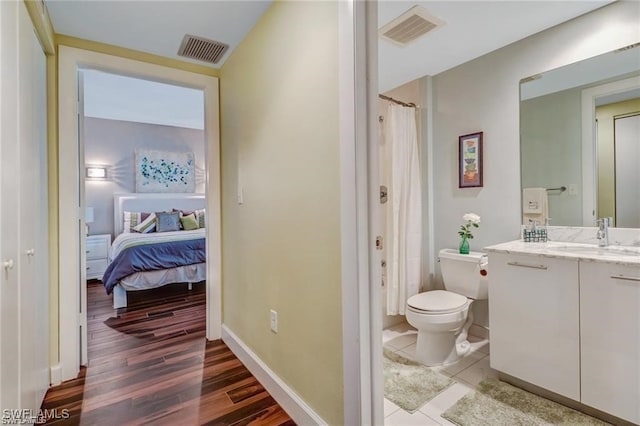 bathroom with toilet, hardwood / wood-style floors, curtained shower, and vanity