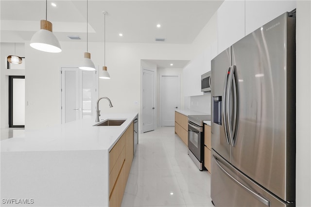 kitchen with a large island with sink, sink, white cabinets, pendant lighting, and appliances with stainless steel finishes