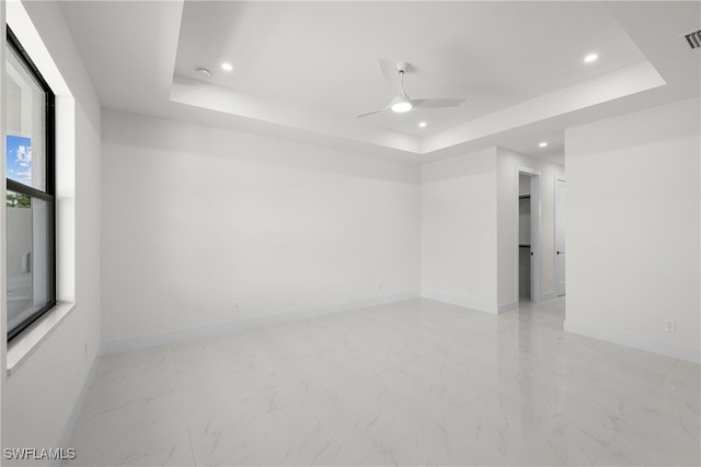 empty room featuring ceiling fan and a raised ceiling