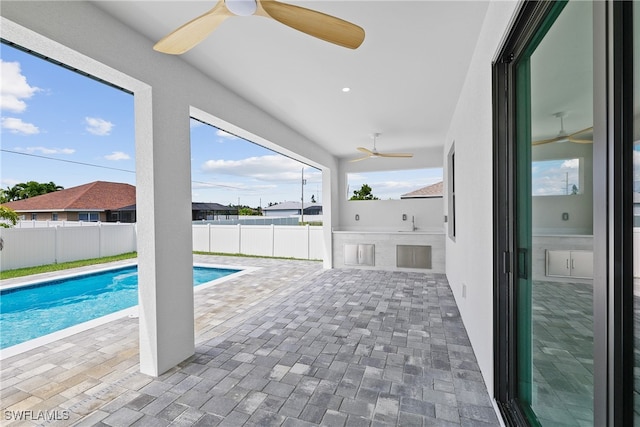 view of swimming pool featuring a patio, exterior kitchen, sink, and ceiling fan