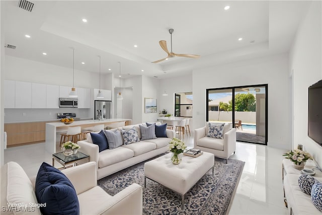 living room featuring ceiling fan and a raised ceiling