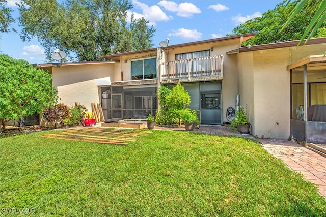 back of house with a balcony, a sunroom, and a yard