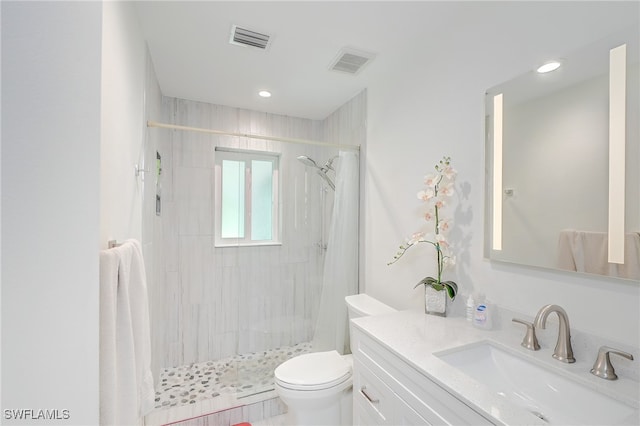 bathroom with a tile shower, vanity, and toilet