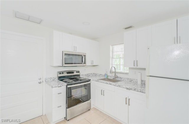 kitchen with stainless steel appliances, white cabinets, light tile patterned floors, and sink