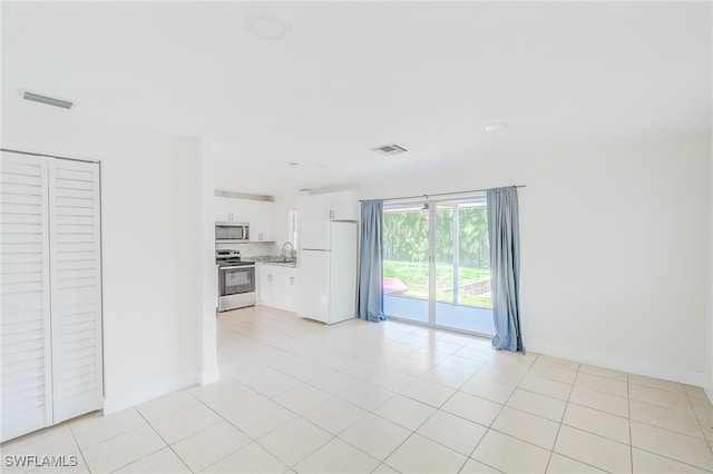 unfurnished living room featuring light tile patterned flooring and sink