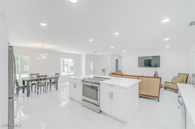 kitchen featuring a center island, stainless steel appliances, hanging light fixtures, and white cabinetry