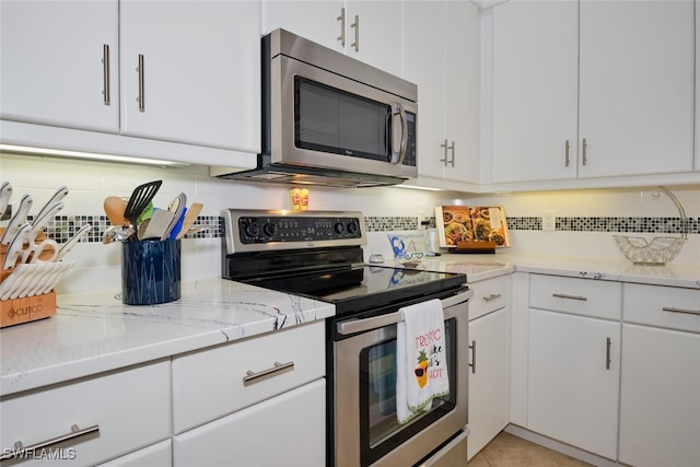 kitchen featuring white cabinets, light stone counters, appliances with stainless steel finishes, and tasteful backsplash