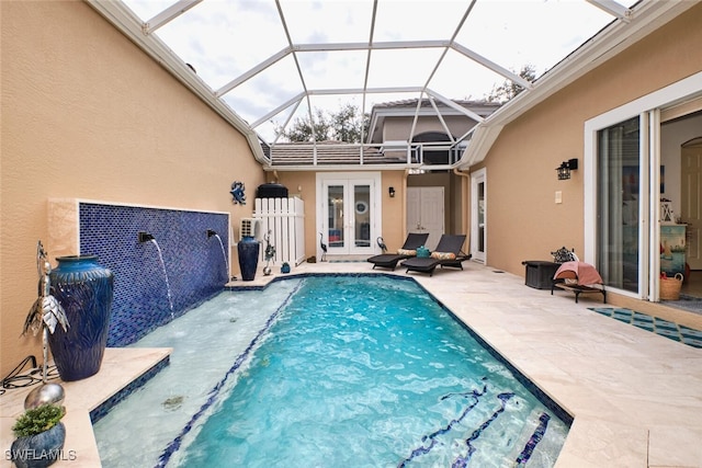 view of pool with glass enclosure, pool water feature, french doors, and a patio