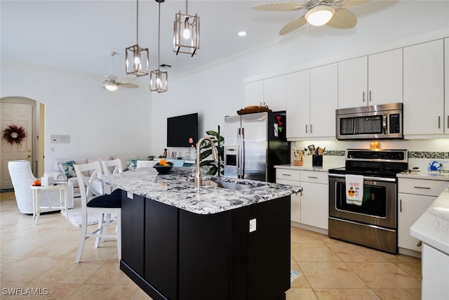 kitchen with pendant lighting, white cabinets, sink, an island with sink, and appliances with stainless steel finishes