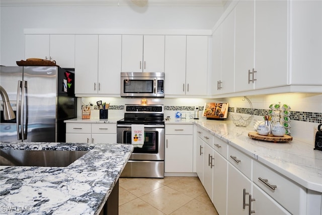 kitchen featuring white cabinets, stainless steel appliances, and light tile patterned floors