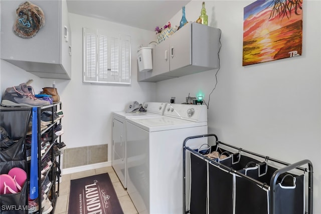 washroom featuring light tile patterned floors, washer and dryer, and cabinets