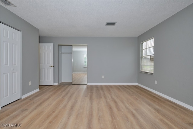 unfurnished bedroom with a textured ceiling and light hardwood / wood-style flooring