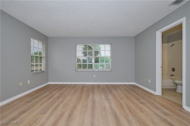 unfurnished bedroom with baseboards, a textured ceiling, visible vents, and light wood-type flooring