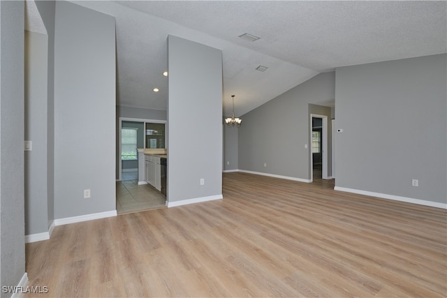 unfurnished living room with a chandelier, a textured ceiling, light wood-type flooring, and vaulted ceiling