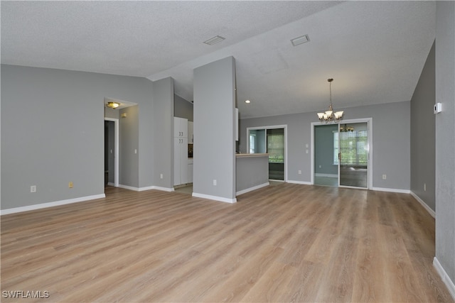 unfurnished living room with light wood-type flooring, lofted ceiling, a textured ceiling, and a chandelier