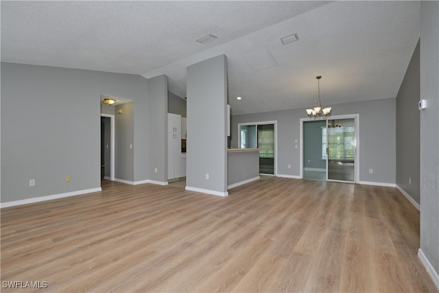 unfurnished living room with lofted ceiling, baseboards, light wood-style floors, and a notable chandelier