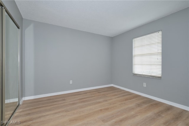 spare room with a textured ceiling and light wood-type flooring