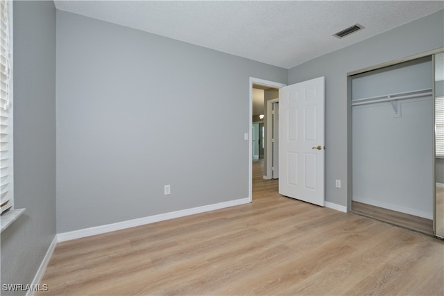 unfurnished bedroom with visible vents, a closet, baseboards, light wood-style flooring, and a textured ceiling