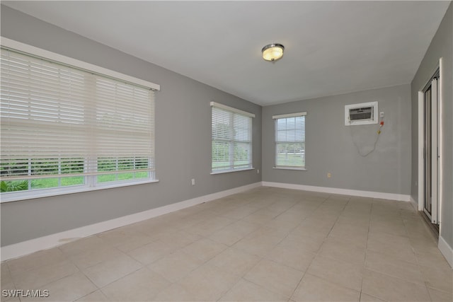 tiled spare room featuring plenty of natural light and a wall mounted air conditioner