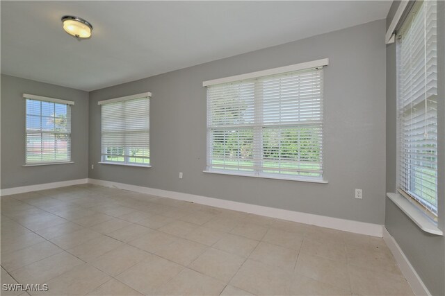 unfurnished room featuring light tile patterned floors, baseboards, and plenty of natural light