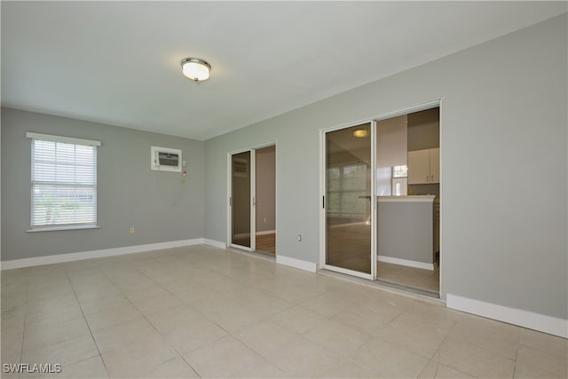 spare room featuring baseboards, a wealth of natural light, and a wall unit AC