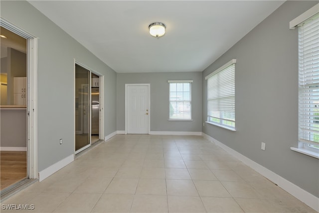 spare room with light tile patterned flooring and baseboards