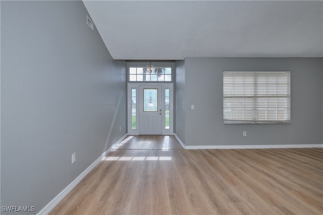 foyer entrance with light wood-style flooring, visible vents, and baseboards