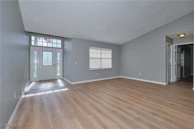 foyer entrance featuring a wealth of natural light, light wood-style floors, and baseboards