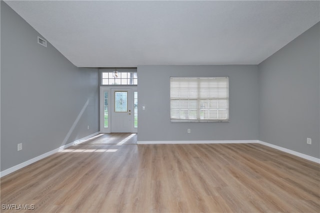 foyer with light wood-type flooring, visible vents, and baseboards