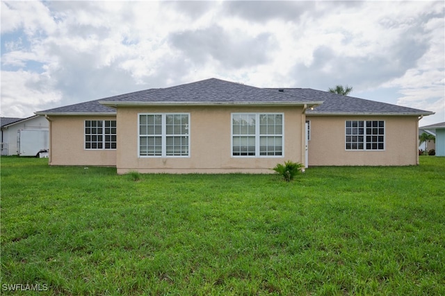 back of property featuring a lawn and stucco siding