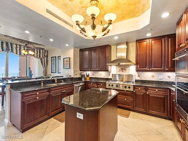 970 Cape Marco Dr Unit 402, Marco Island, FL 34145 - kitchen featuring an inviting chandelier, a tray ceiling, a peninsula, wall chimney range hood, and stainless steel appliances