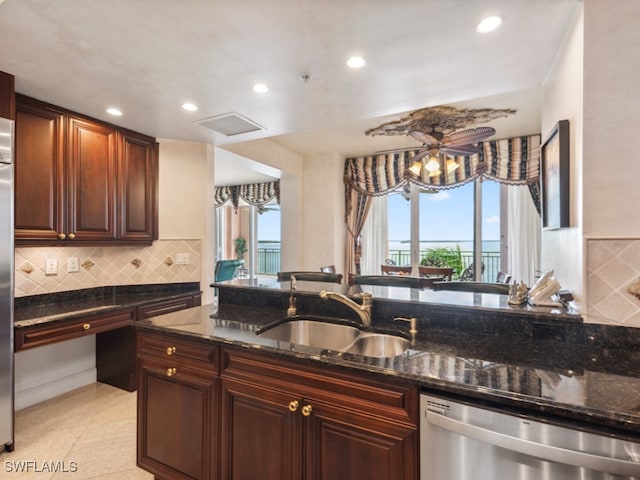 kitchen with dark stone countertops, a wealth of natural light, sink, and dishwasher